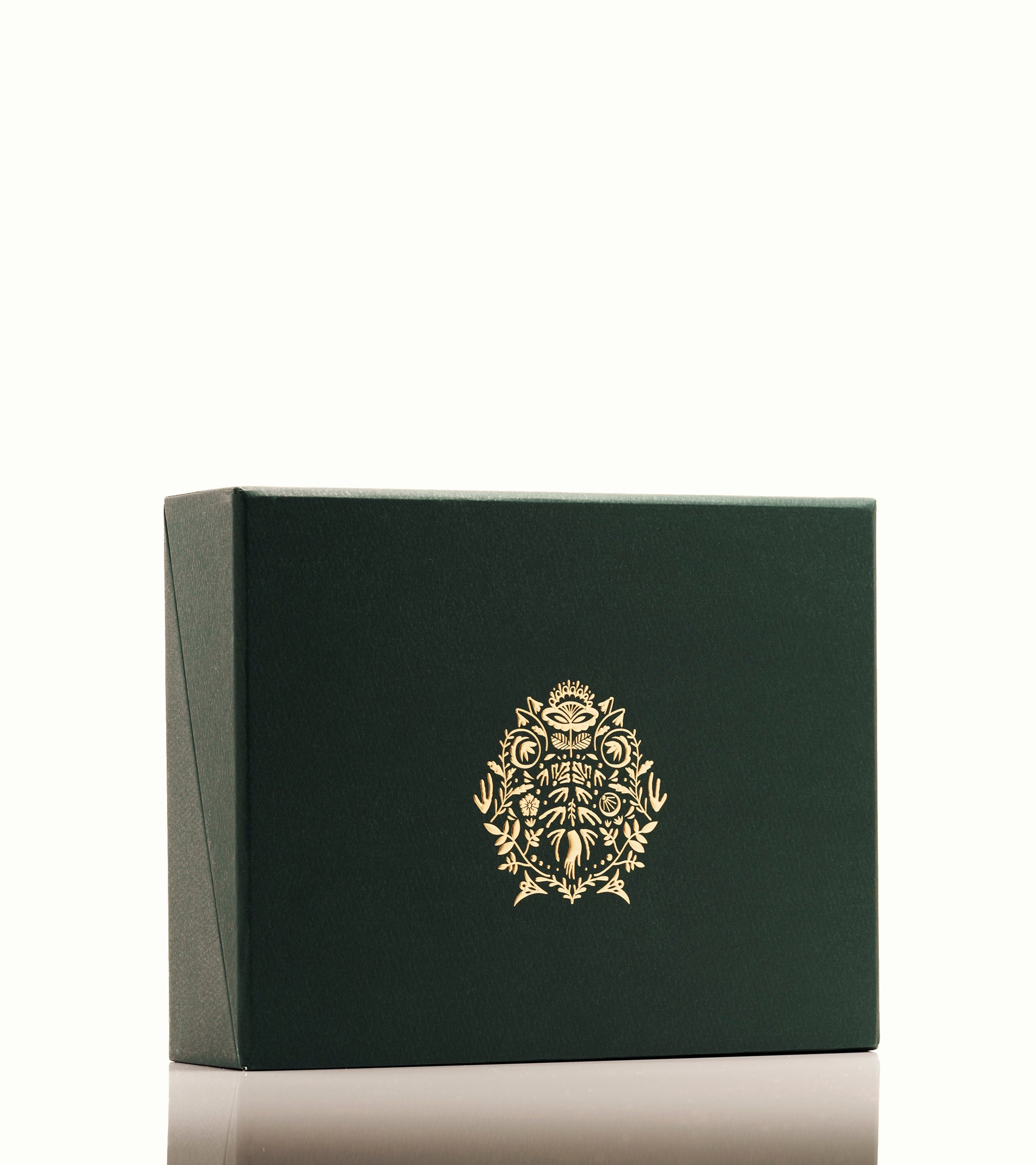 Image of the Nocturnal Skincare box set. The lid is closed and shows the brand crest. The crest is made up of Japanese and Scandinavian design elements. The box is dark green and the crest is metallic gold. 