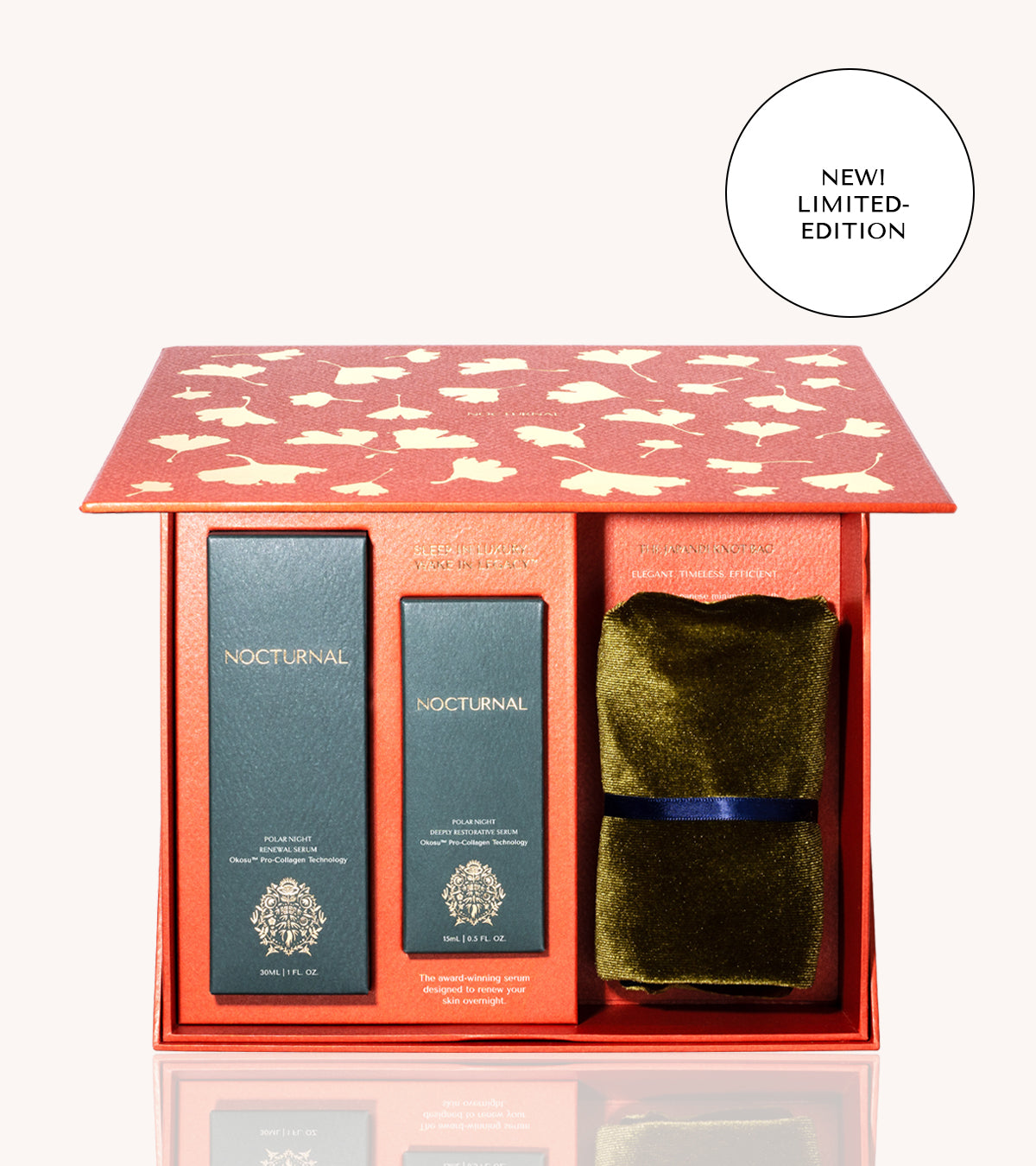 this shows the nocturnal skincare japandi luxury set box open. it is a bright red-orange color with gold metallic gingko leaf pattern on the outside. on the inside, there is a full size 30ml serum and atravel size 15ml serum. plus a japandi knot bag in olive green that is folded and tied with a ribbon.