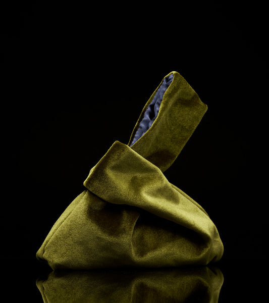 Image of the Japandi Japanese knot bag sitting on a surface. It is an olive green bag made out of Scandinavian velvet. 