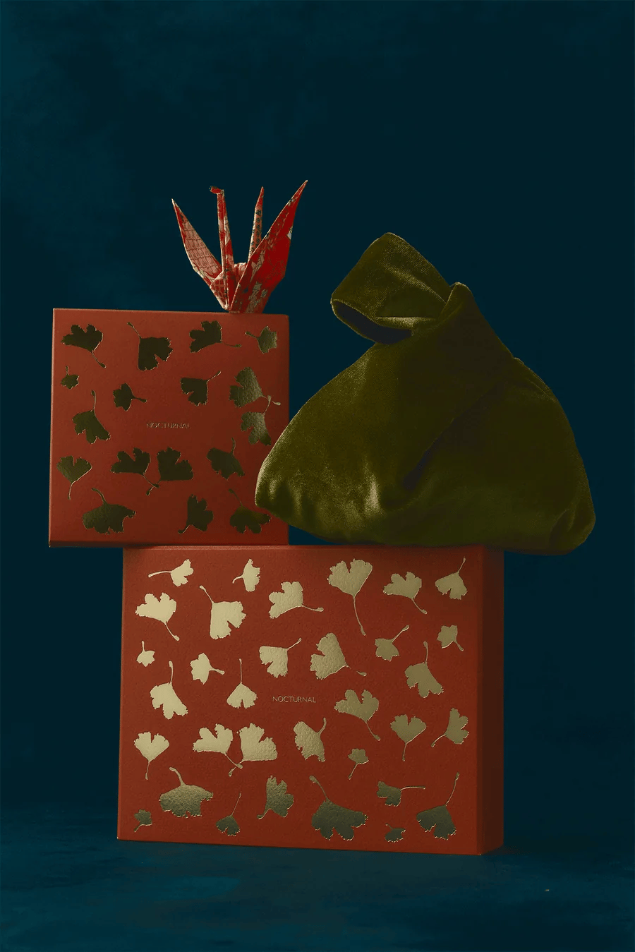 Nocturnal holiday gift boxes with gold ginkgo leaves, a velvet Japandi Knot Bag and a paper crane