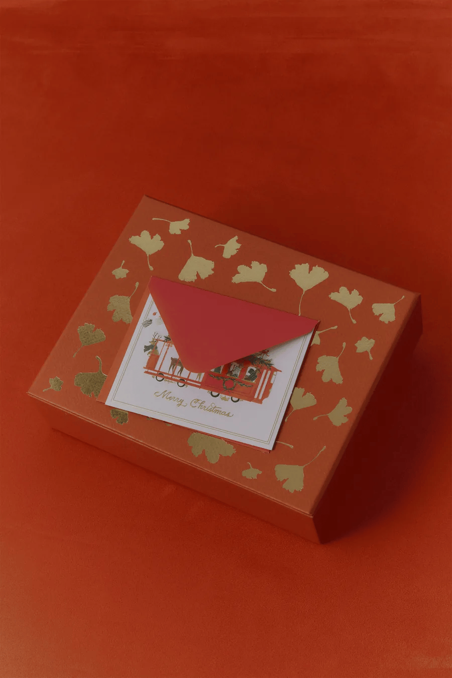 Nocturnal holiday gift box in red with gold ginkgo leaves and a Merry Christmas card